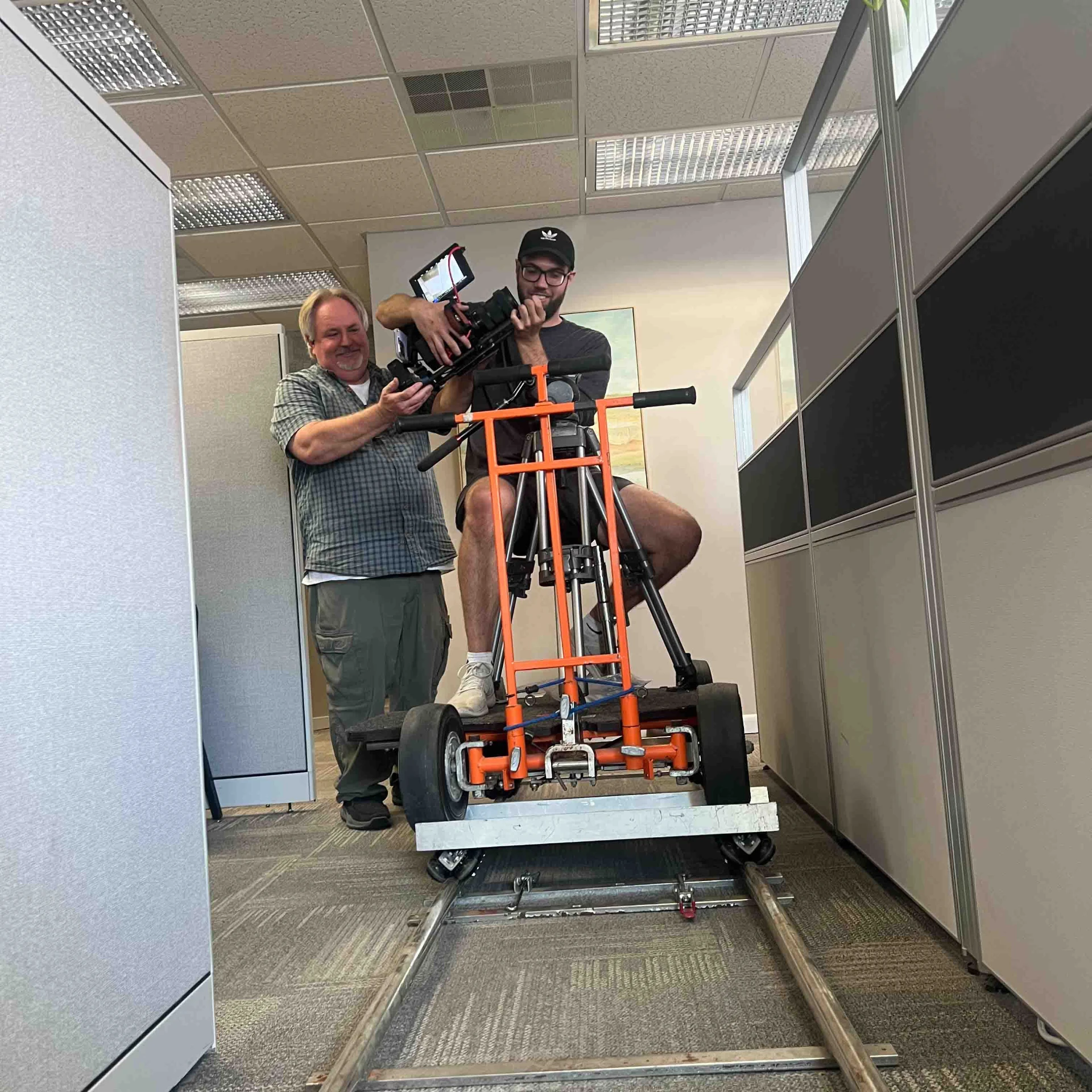 Ashton Gillett riding a dolly on track for an office interior shoot