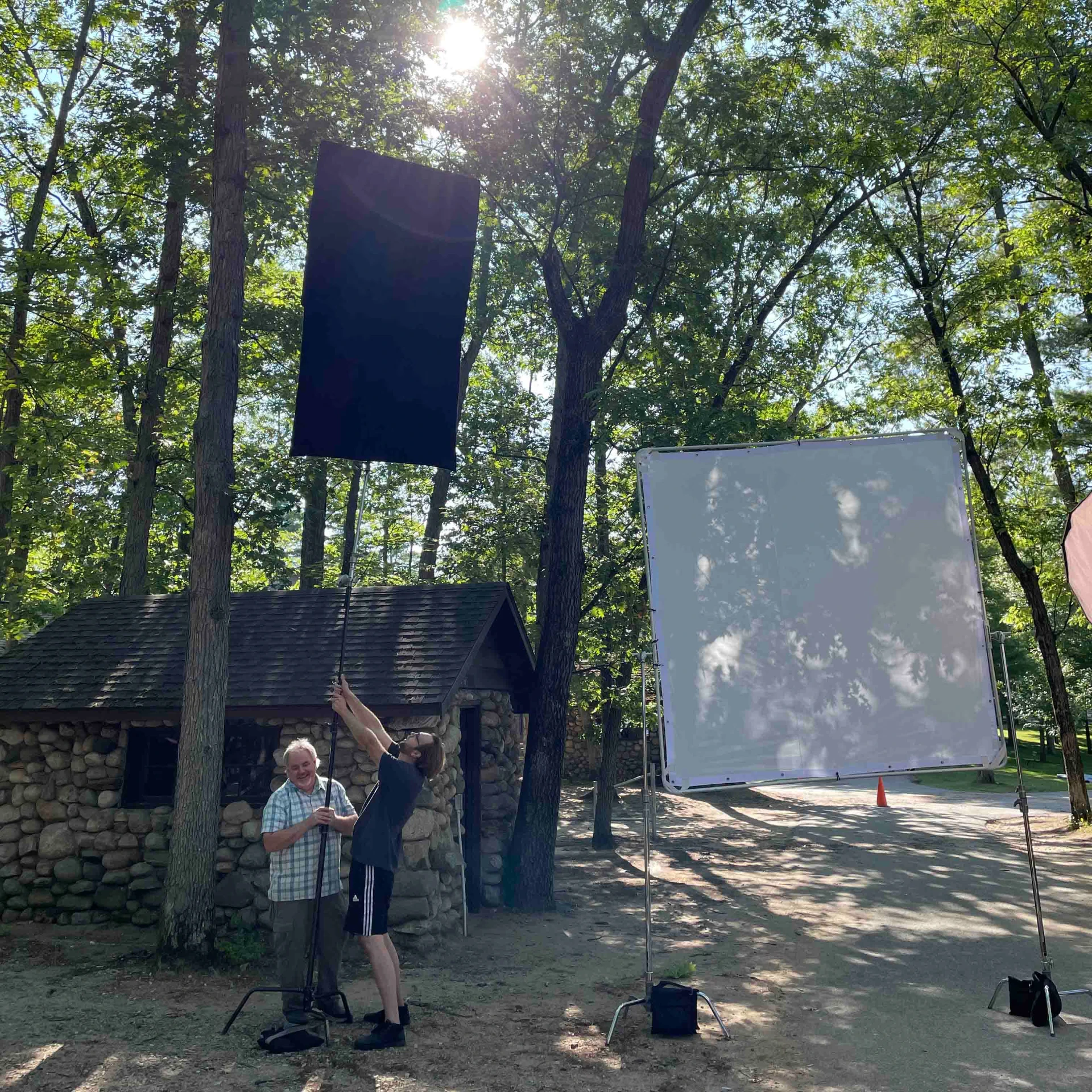 Crew flagging sunlight with a floppy and diffusion frame on location