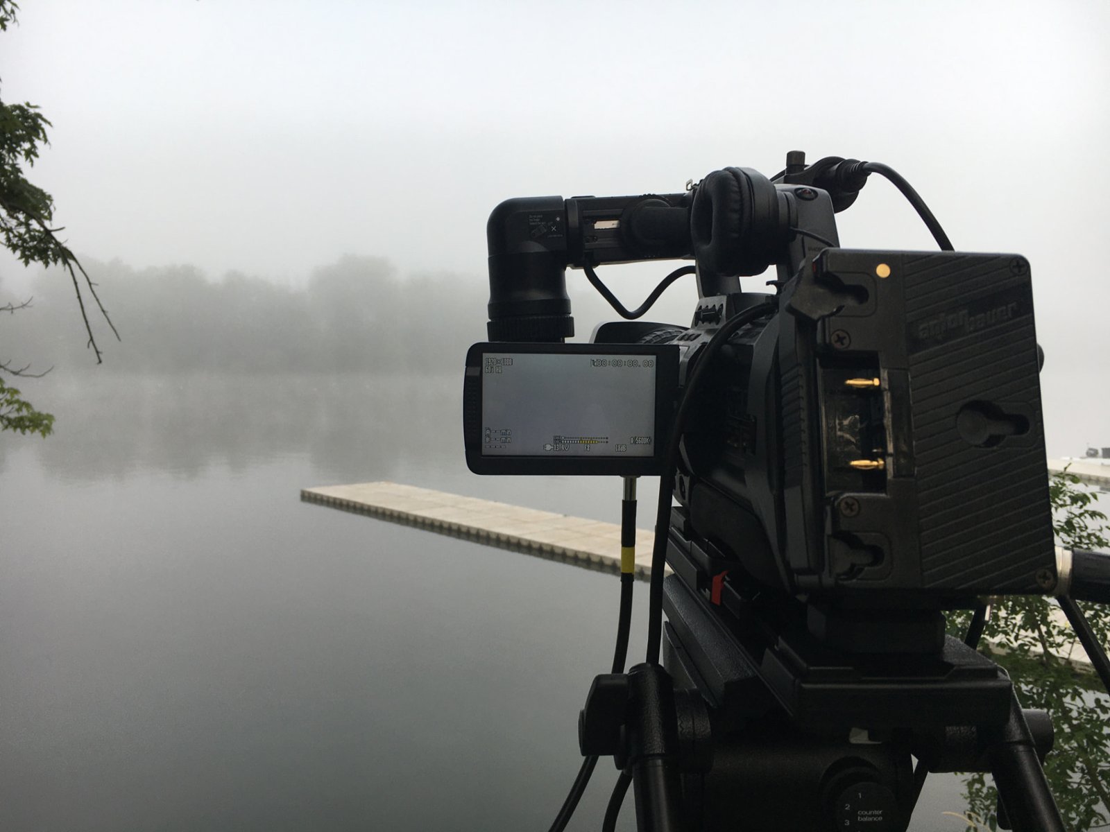Broadcast camera framing a foggy lake at sunrise
